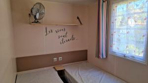 a room with a bed with a window and a fan at Mobil-home 3 chambres climatisé sur le domaine 4 étoiles Rivages des Landes in Aureilhan