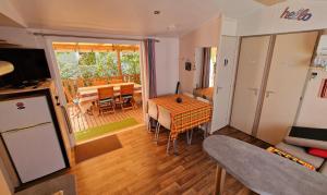 a living room with a table and a balcony at Mobil-home 3 chambres climatisé sur le domaine 4 étoiles Rivages des Landes in Aureilhan