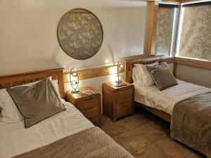 two beds in a room with two lamps and a mirror at Nautilus Tenby in Tenby
