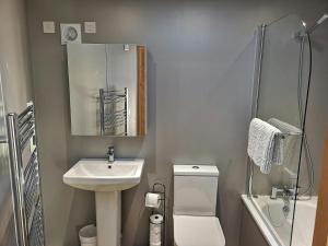 a bathroom with a sink and a toilet and a mirror at Nautilus Tenby in Tenby