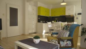 a living room with a table and a kitchen with yellow cabinets at Apartment Sophie in Plovdiv