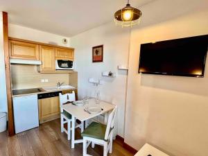 a small kitchen with a small table and a tv on the wall at Seven Keys - Le cocon des neiges in Valmeinier