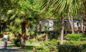 a woman riding a bike in front of a house at Mobil-home 6 pers, tout confort Clim, piscine & animations in Agde