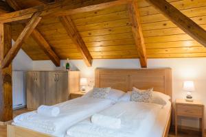 a bedroom with two white beds with wooden ceilings at Apartmány Mezivodí in Kyčera