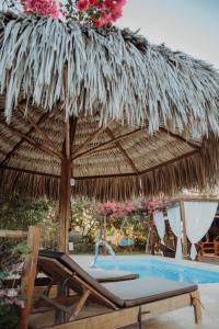 a straw umbrella and a chair next to a swimming pool at Vila hangloose vista da lagoa in Acaraú