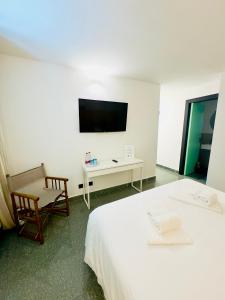 sypialnia z 2 łóżkami, telewizorem i krzesłem w obiekcie Amoredimare B&B in Villa w mieście Polignano a Mare