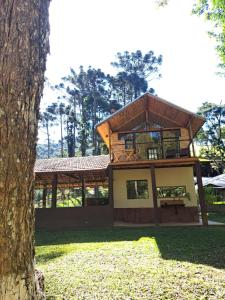 a house with a wrap around porch next to a tree at Recanto Do Sapucaí in Sapucaí-Mirim