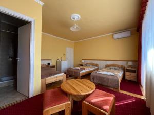 a room with two beds and a table and chairs at Gyógygödör Vendégház in Szekszárd