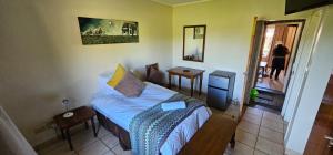 Un pequeño dormitorio con una cama y una mesa. en Casa Del Sol Guesthouse, en Lime Acres