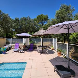 a patio with chairs and an umbrella and a pool at Studio Romance dans la nature in Carnoules