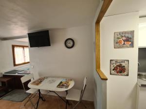 a kitchen with a table and a clock on a wall at Studio Romance dans la nature in Carnoules