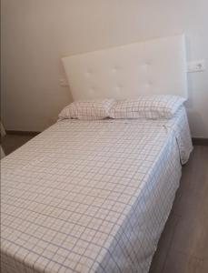 a bed with a checkered blanket and two pillows at Increible apartamento en primera linea de playa in Puerto de Gandía