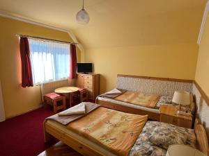 a room with two beds and a desk and a tv at Gyógygödör Vendégház in Szekszárd +61 photos