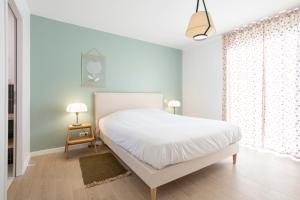 a bedroom with a white bed and a window at Villa Lande - 180m de la plage in Penmarcʼh