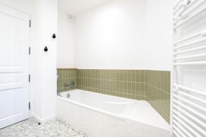 a bathroom with a white tub and green tiles at Villa Lande - 180m de la plage in Penmarcʼh +23 photos