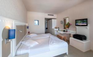 a bedroom with a white bed and a television at Calimera Yati Beach in Midoun