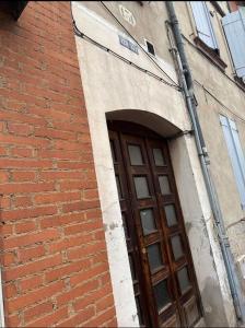a door to a brick building with an arch at L'étage de l'Aristide proche gare parking facile in Montauban