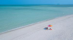 two people sitting under an umbrella on a beach at Arista Villa in Ukulhas