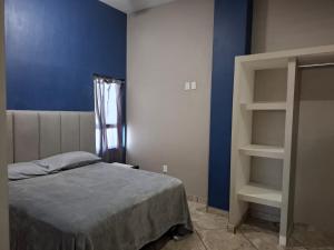 ein Schlafzimmer mit einem Bett und einer blauen Wand in der Unterkunft Departamentos La roca D2 in La Peñita de Jaltemba