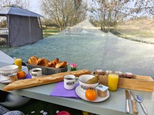 a table with a tray of bread and orange juice at La bulle in Attiches