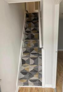 a hallway with a staircase with a geometric rug at Crossgar Holiday Home in Crossgar
