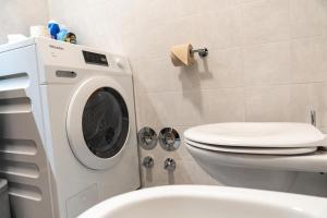 a bathroom with a washing machine next to a toilet at Flow Apartments WOLKENSTEIN in Merano