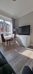 a living room with a table and a large television at Carrick - One Bed Apartment in Largs