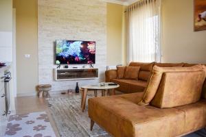 a living room with a couch and a flat screen tv at J & J Holiday Home Vala Mar in Hamallë