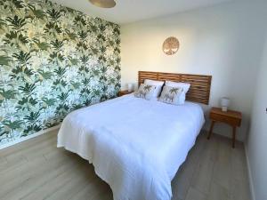 Rivière-Saas-et-GourbyBelleVue - Jardin-Montagne-Calme的卧室配有一张白色大床和花卉壁纸