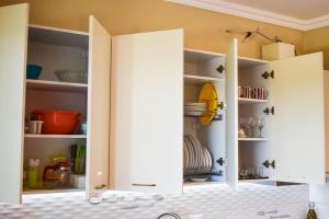 a kitchen with white open cabinets with dishes at J & J Holiday Home Vala Mar in Hamallë +10 photos