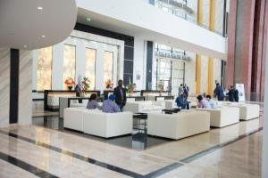 un hall avec des personnes assises sur des canapés dans un bâtiment dans l'établissement Grand Hotel Djibloho, à Djibloho