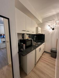 a kitchen with white cabinets and a black counter top at Au ColbVert - La Catho' - Vauban - Métro - Netflix - Wifi in Lille
