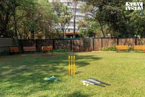 a game of cricket in a yard with benches at Mehta Mansion by StayVista - A Villa with a Swimming Pool and Pool Table in Lonavala