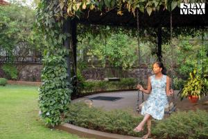 a woman in a dress on a swing in a garden at Mehta Mansion by StayVista - A Villa with a Swimming Pool and Pool Table in Lonavala +57 photos