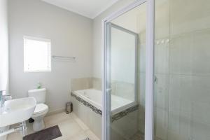 a bathroom with a shower and a toilet and a sink at Founders Villa in Britannia Bay +27 photos