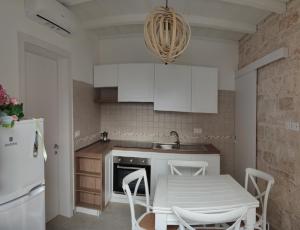 a kitchen with white cabinets and a table with chairs at Antica Dimora Vada' in Alberobello