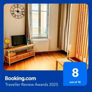 a living room with a television and a clock on the wall at STUDIO COSY Gare & centre-ville in Saumur