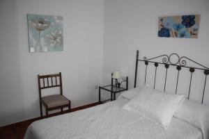 a bedroom with a white bed and a chair at La Cruz Verde in Tembleque