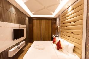 a bedroom with a large bed with a tv on the wall at Nachi Grand Residency in Devakottai