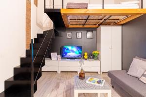 a living room with a television and a staircase at Casa Volturno - 5 min dalla stazione in Monza