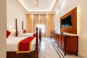 a bedroom with two beds and a flat screen tv at Brij Castle in Jaipur