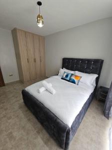 a bedroom with a large bed with a black headboard at Treands Apartments in Nakuru