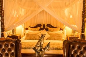 a bedroom with a canopy bed with two chairs at Elandela Private Game Reserve and Luxury Lodges Pty Ltd in Hoedspruit +191 photos