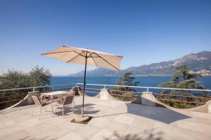 a table and chairs with an umbrella on a balcony at Villa Cesarina-Vista lago totale in Brenzone sul Garda