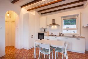 a kitchen with white cabinets and a table and chairs at Villa Cesarina-Vista lago totale in Brenzone sul Garda