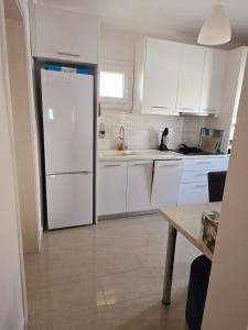 a kitchen with white cabinets and a white refrigerator at Apartment sofia sea view in Nea Vrasna