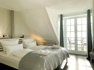 a bedroom with a bed with two white flowers on it at Huus Lüttenblick Whg Amrumblick in Südstrand +8 photos