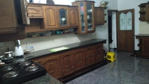 a kitchen with wooden cabinets and a stove at Aryabhadhra Cottages 7, Room-4 in Ernakulam