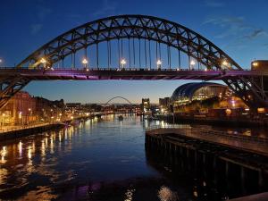 a bridge over a river at night with lights on at All Saints Apartments 5A by Week2Week in Newcastle upon Tyne