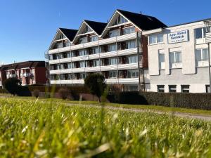 a large apartment building in front of a grass field at Haus Seepferdchen in Schillig